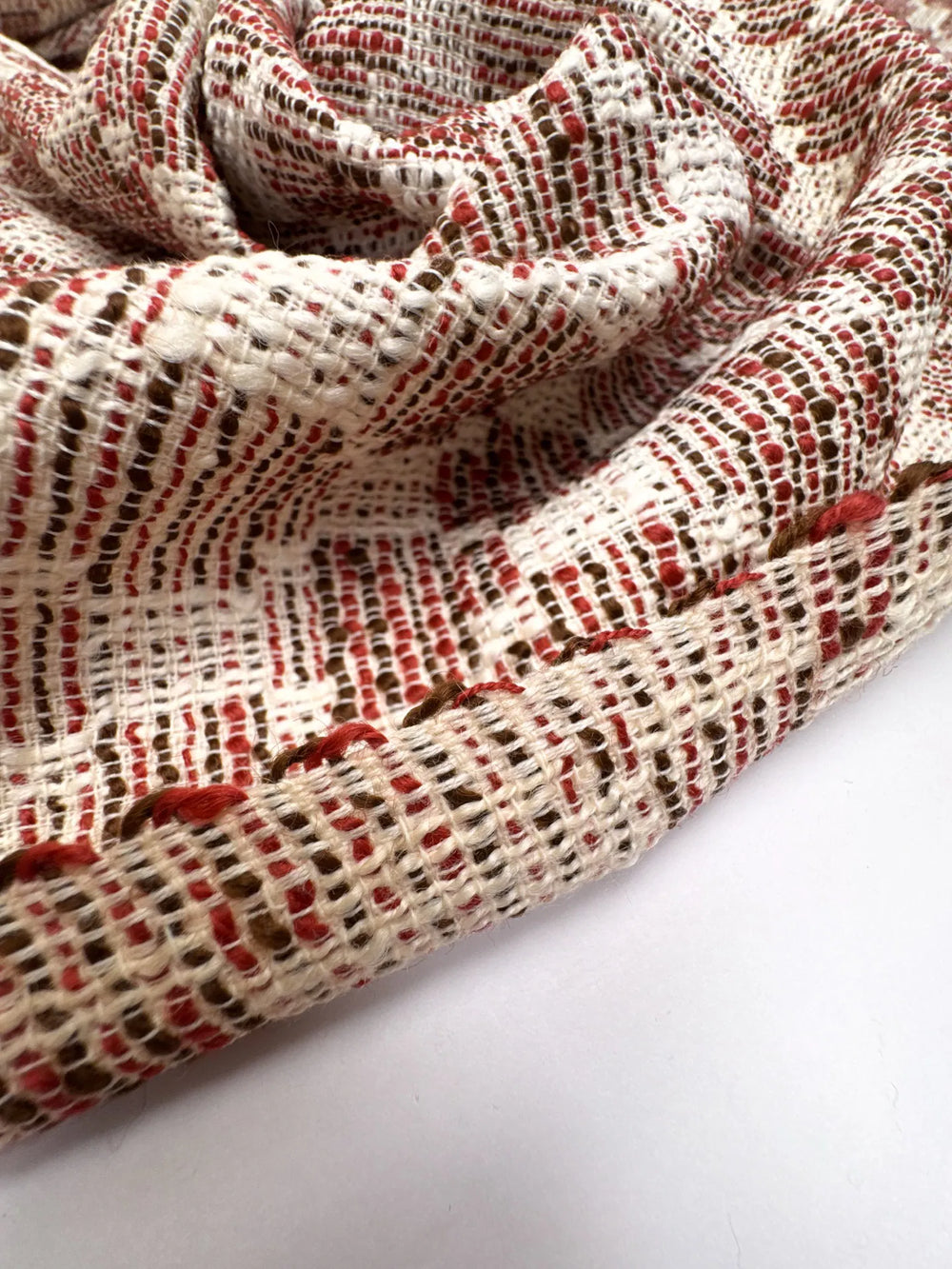 Premium Wool Boucle fabric in cream, red, and black cross-texture. Made from 85% Wool and 15% Cotton. Ideal for suiting, coats, and structured dresses.