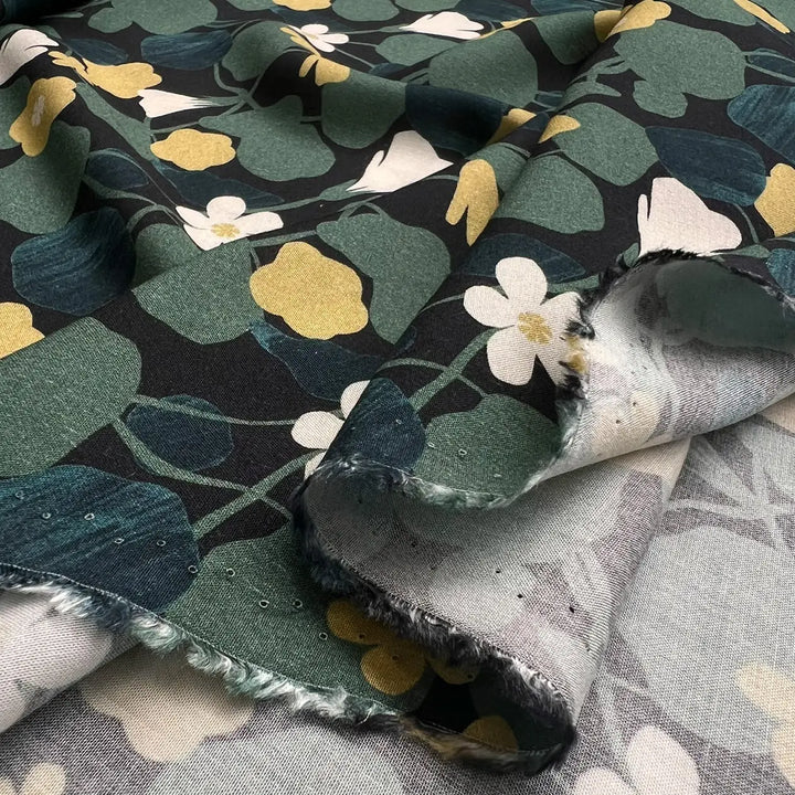 Viscose Challis fabric featuring Capucine flowers pattern in black, green, and yellow, perfect for dresses, skirts, and blouses.