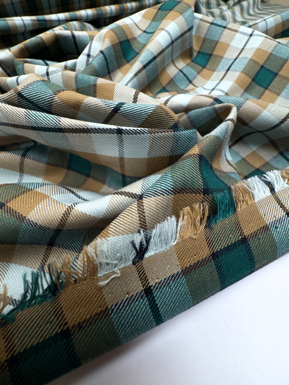 Italian cotton tweed fabric in cream, green, and brown plaid twill weave, lightweight and structured for coats, suiting, and dresses.