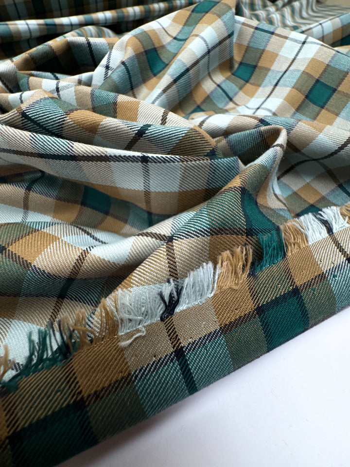 Italian cotton tweed fabric in cream, green, and brown plaid twill weave, lightweight and structured for coats, suiting, and dresses.