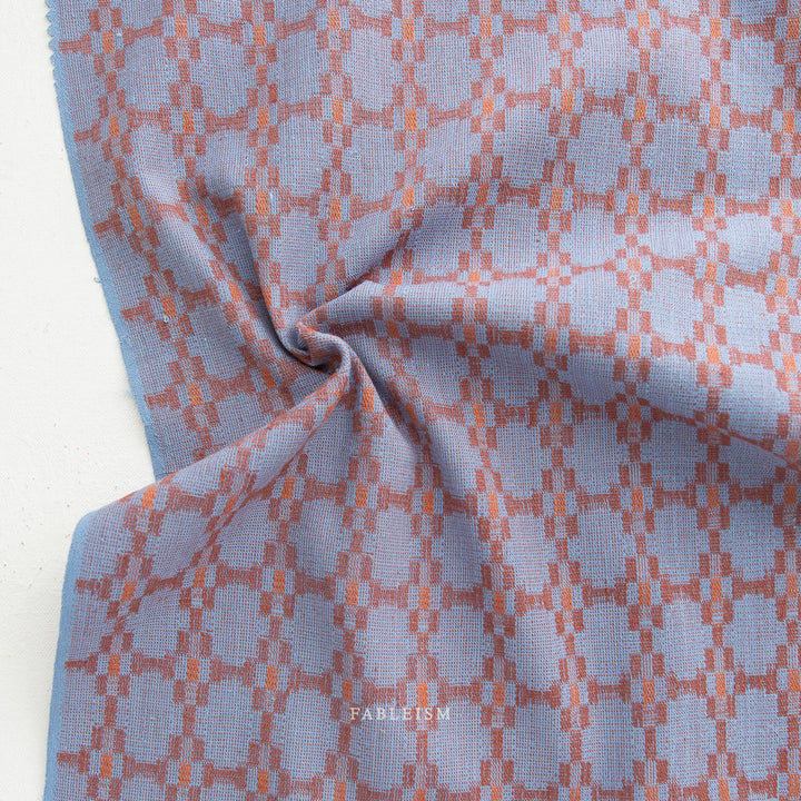 Cotton woven fabric in monarch grove design with blue and rust tones – 100% cotton material for shirts, blouses, dresses, and skirts.