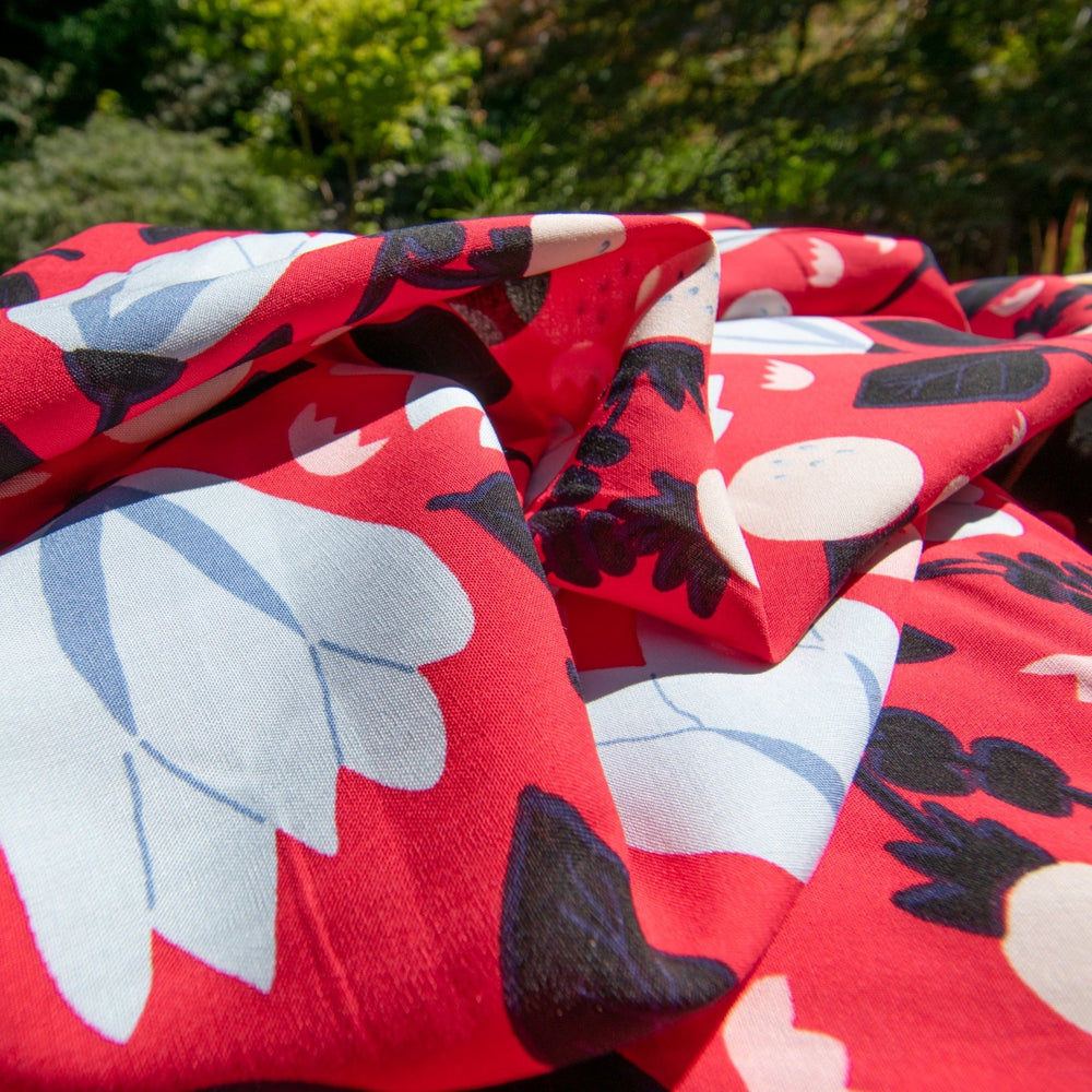Rayon Poplin fabric with blue floral pattern on red background, 100% lightweight, soft and drapable, ideal for sewing projects.